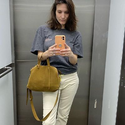 Ortal Ben-Shoshan is wearing grey tees, white pant, and holding a big handbag in the picture.